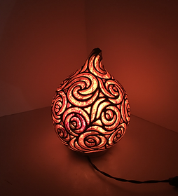 Hand carved illuminated gourd lamp with intricate and abstract design, creating a warm glowing effect