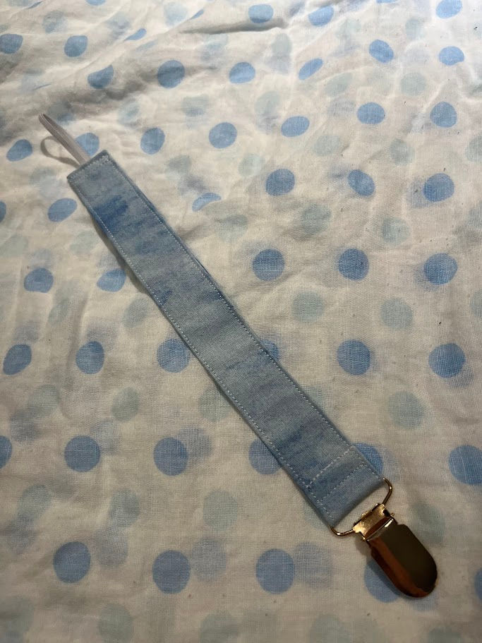 Thumbnail: an image of a blue cotton dummy clip and a white muslin swaddle with blue dots