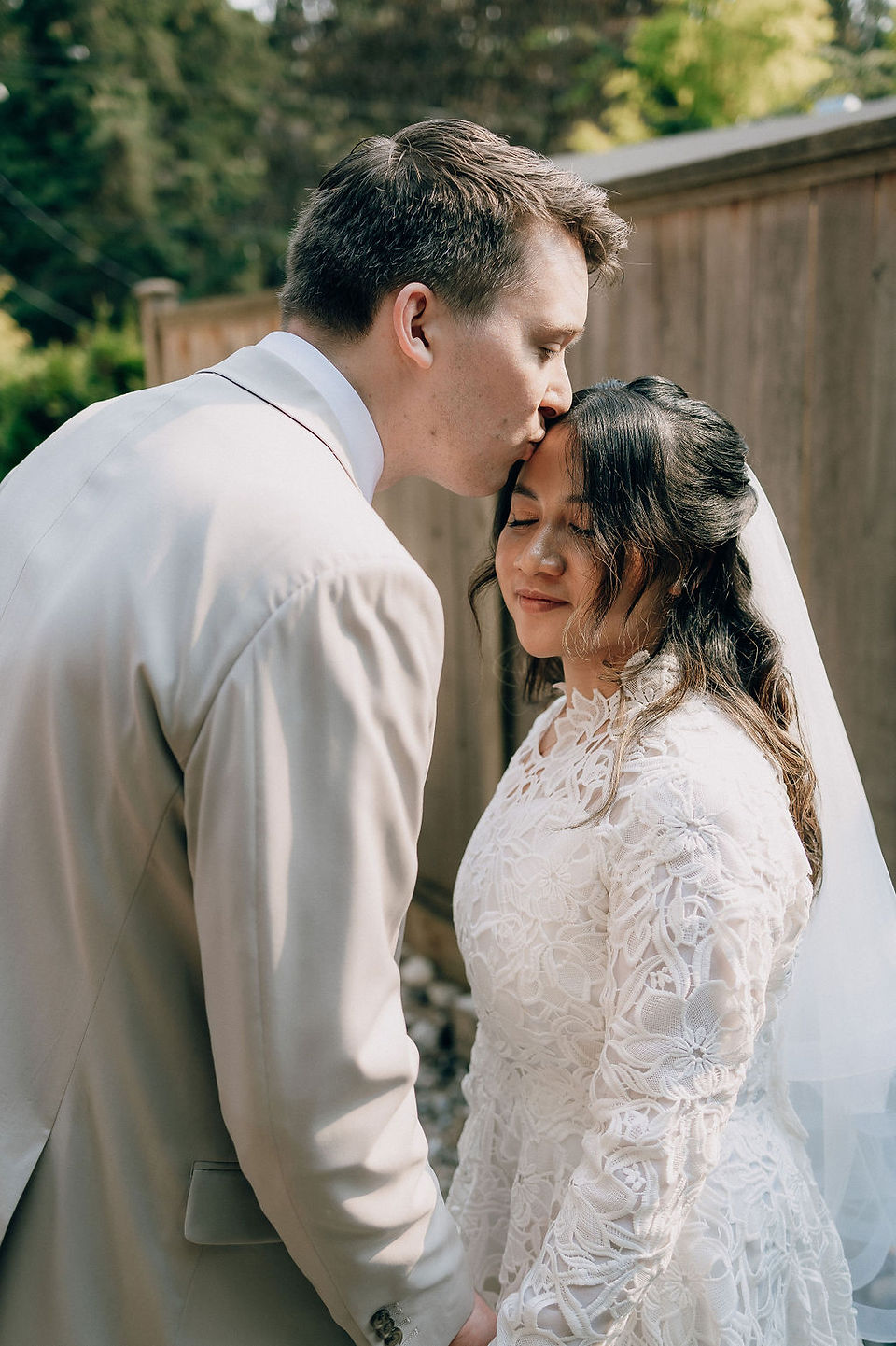 Portrait of groom sweetly kissing the bride's forehead 