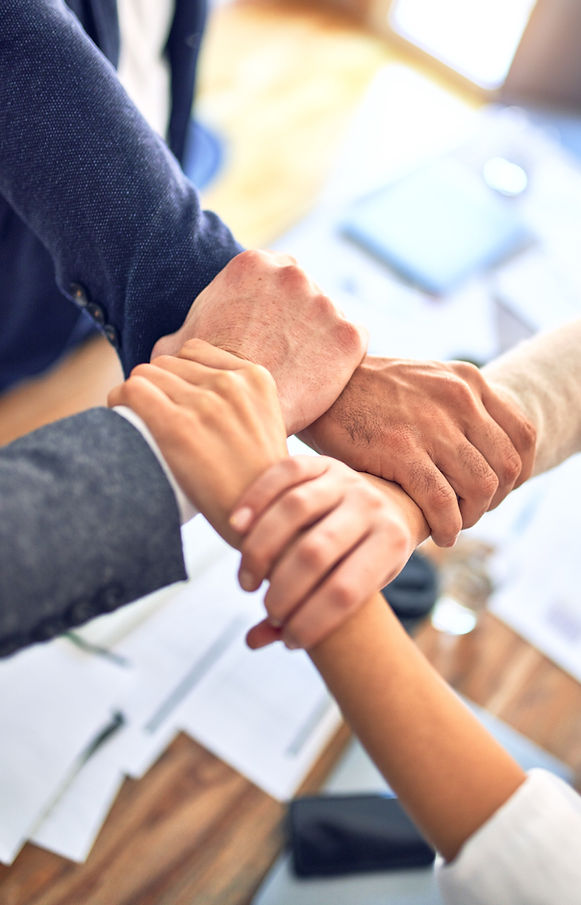 Group of business workers standing with hands together doing symbol at the office_edited.j