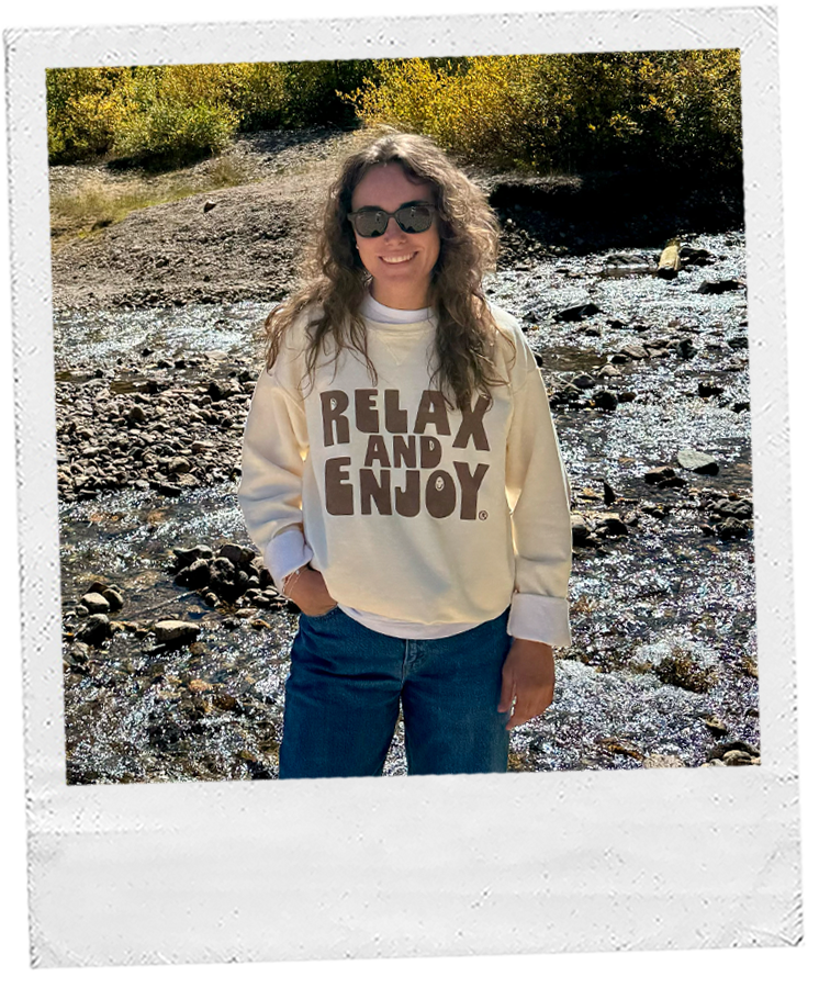 Thumbnail: girl standing by a mountain river, wearing a cream sweatshirt with "relax and enjoy." cute neutral aesthetic sweatshirt