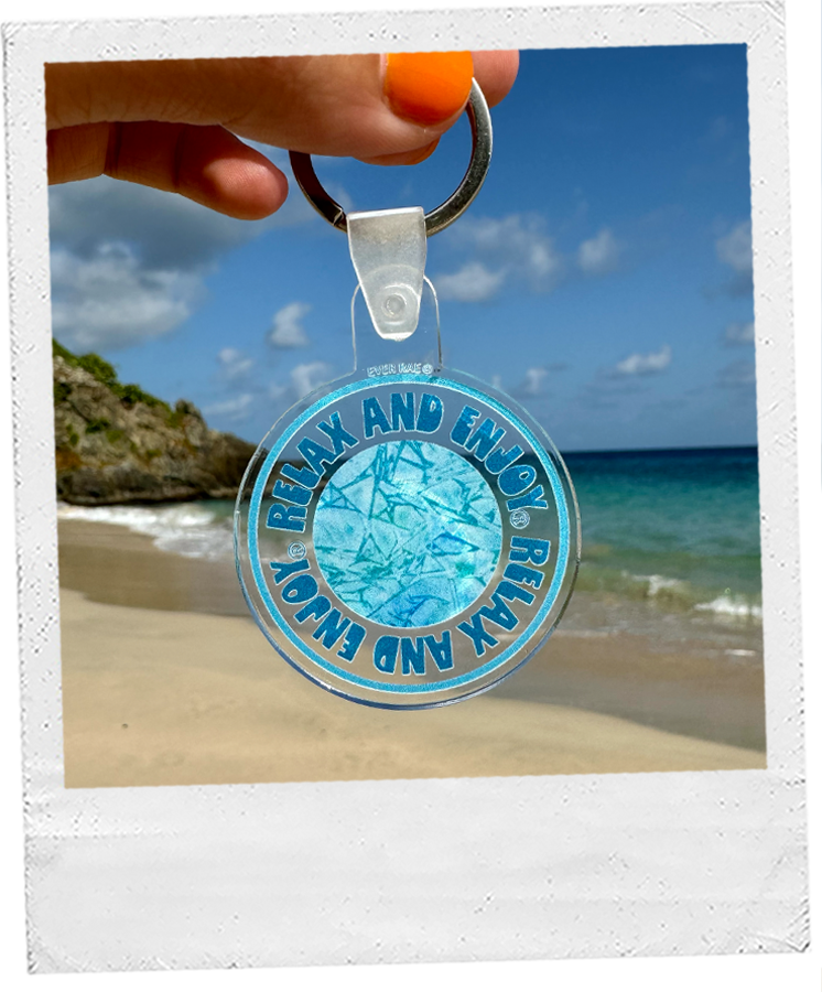acrylic "relax and enjoy" keychain featuring blue watercolor artwork, background is a tropical beach with blue water and sand
