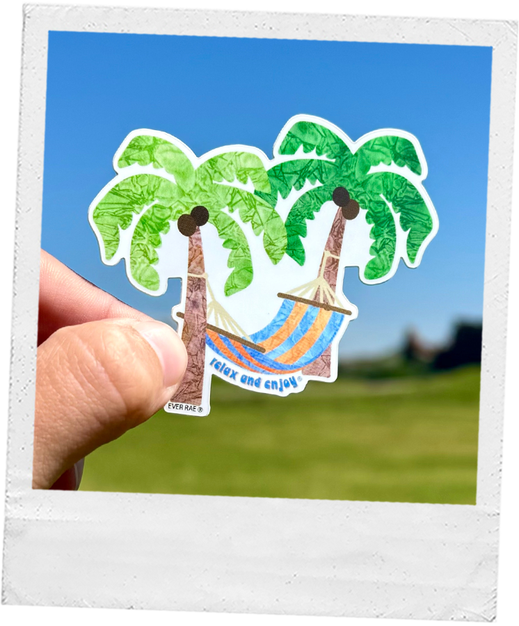 Thumbnail: Hand holding watercolor paint sticker that features a blue and orange striped hammock between two vibrant green palm trees.