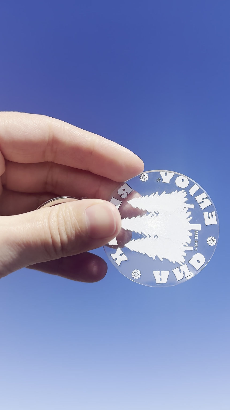 Thumbnail: video showing the front and back of an acrylic keychain to show the green pine trees on the front and the plain white back