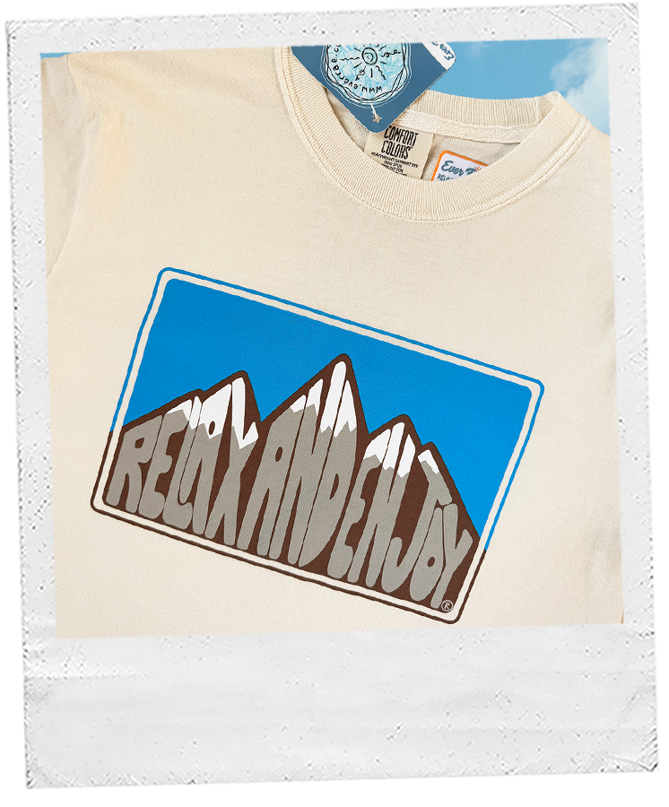 Thumbnail: Off-white t-shirt with brown and blue mountain graphic and “RELAX AND ENJOY®” text in block letters.