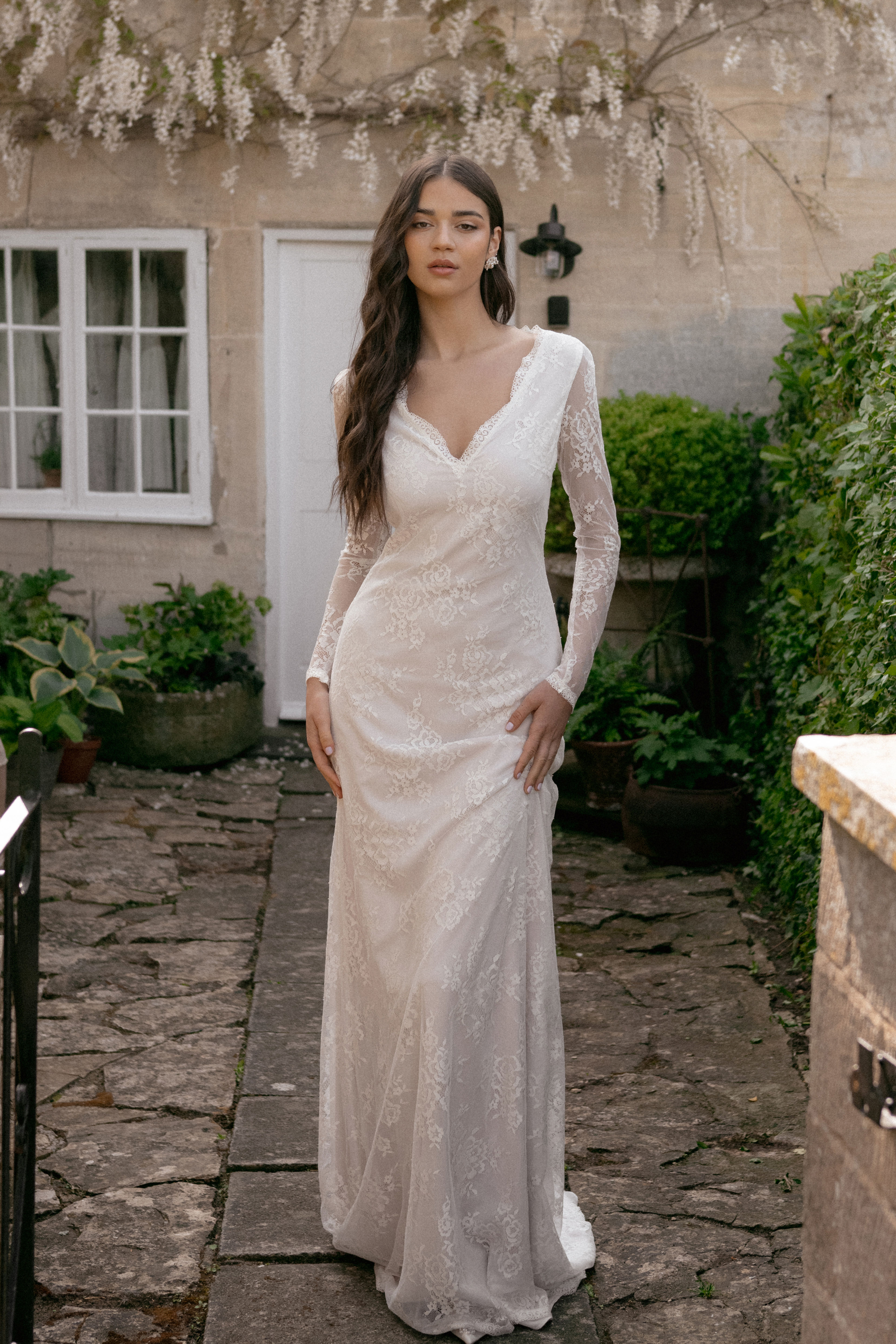 Bride Wearing a fitted lace, 'v' neck wedding gown with lace sleeves and a nude layer beneath the lace.