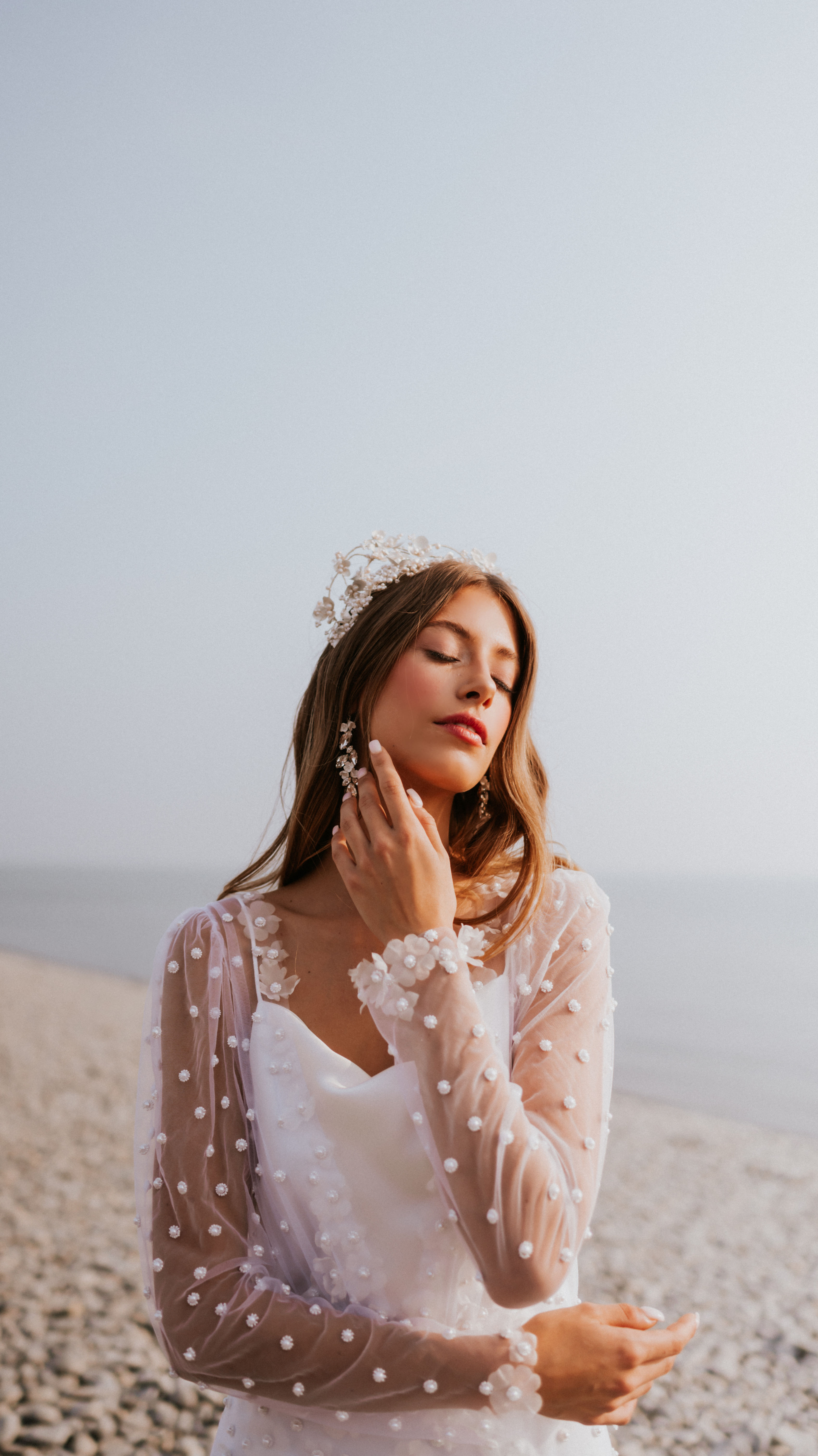 Front of Breeze, a beaded pearl wedding dress featuring a belted overlay with pearl buttons and a satin underslip