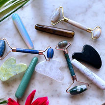 Facial rollers, facial wand and gua shas laying on marble table