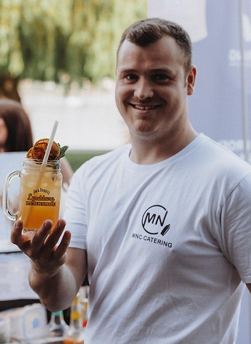 Manuel Niedermaier mit einem Cocktail auf einem Sommerevent mit MNC Catering Shirt