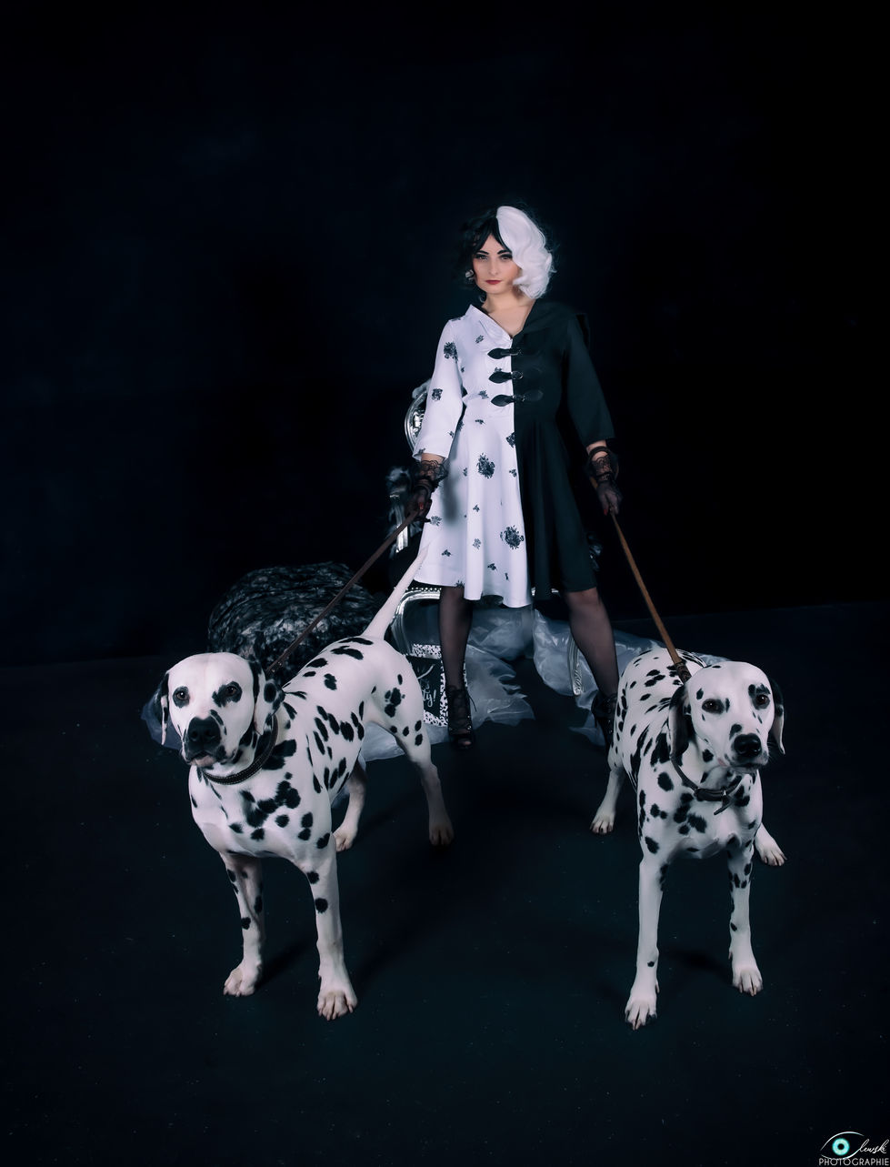Photographie portrait de deux chiens dalmatien et de leur maitresse déguisée en Cruella d'Enfer