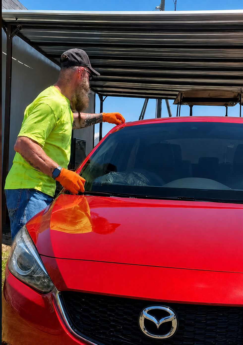 Technician in high-vis shirt repairing a red car