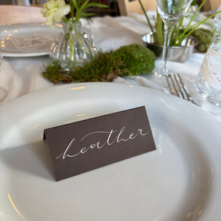 A brown place setting on a white plate at a formal wedding table setting
