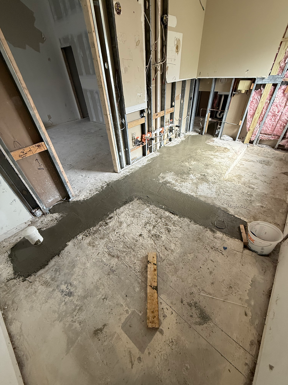 Residential construction services showing floor plumbing trench backfill process.