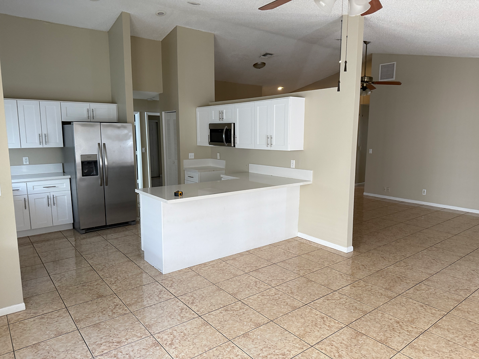 Outdated kitchen remodel with white cabinets and tile floor.