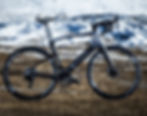 จักรยานเสือหมอบไฟฟ้า (e-road bike) สีดำจอดบนพื้นหิน ฉากหลังภูเขาหิมะตระการตา
