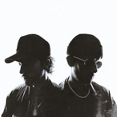 Two men in profile against a white background, wearing dark caps. One has sunglasses and a chain. The mood is mysterious and edgy.