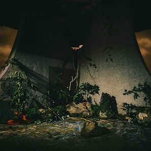 Dark, moody scene of a huge concrete structure overgrown with vines, surrounded by rocks, plants, and shallow water.