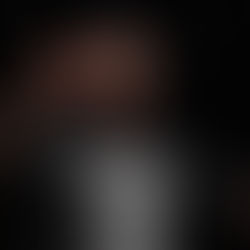 Man on stage giving thumbs up, wearing "IMMOLATION" t-shirt. Dark background, microphone visible. Joyful expression.