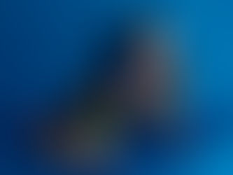 A woman covered in colorful body paint poses on a blue background, casting a shadow. Her expression is calm and contemplative.