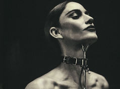 Silhouetted person with a collar gazing upward in a dramatic pose against a dark background, evoking a mysterious, intense mood.