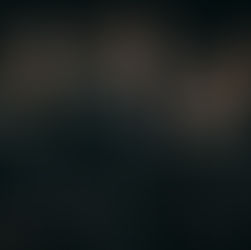 Four people in studded black outfits stand confidently against a dark background, exuding a rock or metal vibe.