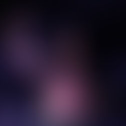 Jessie Reyez joyfully holding microphone on stage, wearing polka-dot outfit. Dark background with spotlight, creating an energetic, vibrant atmosphere.