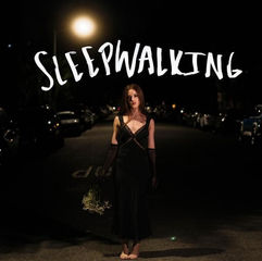 Woman in black dress walking barefoot at night on a dimly lit street. Holding flowers. "SLEEPWALKING" text above, mysterious mood.