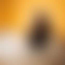 Teen girl with headphones and a black jacket sits on a bed in a yellow room, surrounded by scattered pages, looking contemplative.