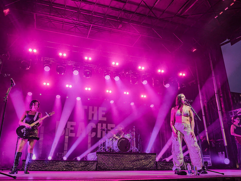 Band performs onstage under vivid pink lights, with THE BEACHES backdrop and an energetic concert atmosphere.