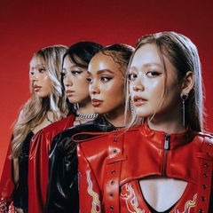 Four women in red and black outfits stand in profile against a vivid red background, exuding confidence.