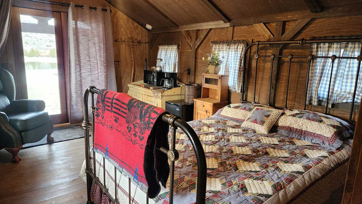 Cozy rustic cabin bedroom with a metal bed and quilt at Hangman’s Guest Ranch