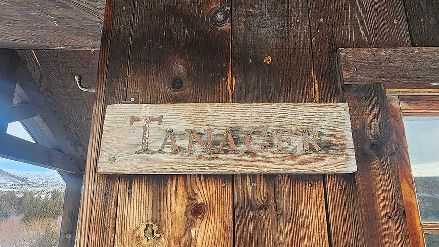 Carved "Tanager" sign on rustic wood at Hangman’s Guest Ranch