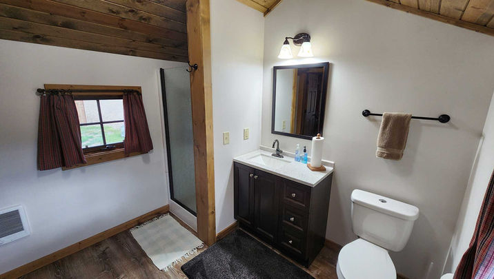 Rustic cabin bathroom with shower, toilet, and vanity at Hangman’s Guest Ranch