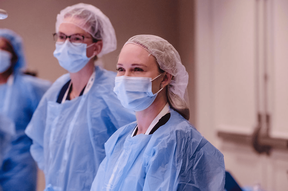 Attendees in surgical caps, masks and gowns during a hands-on session at a corporate meeting