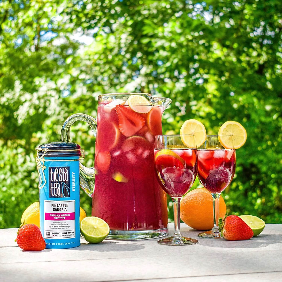 Jug and glasses full of bright red ice tea with fresh fruit slices