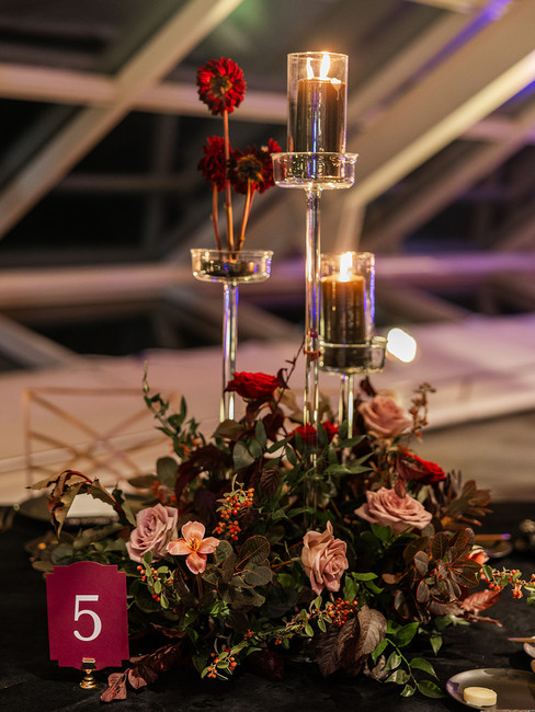 Elegant red and mauve flower decor on black tablecloth at wedding reception