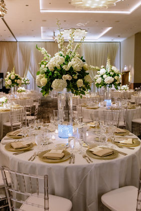 Tall white hydrangea and rose centerpiece in glass cylinder vase with gold charger plates and crystal chiavari chairs, Chicago wedding designed by Frank Event Design