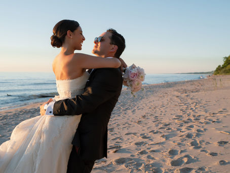 Bride and groom sharing a joyful lift at golden hour, pink peony bouquet in hand, at a lakeside Chicago wedding styled by Wedicity