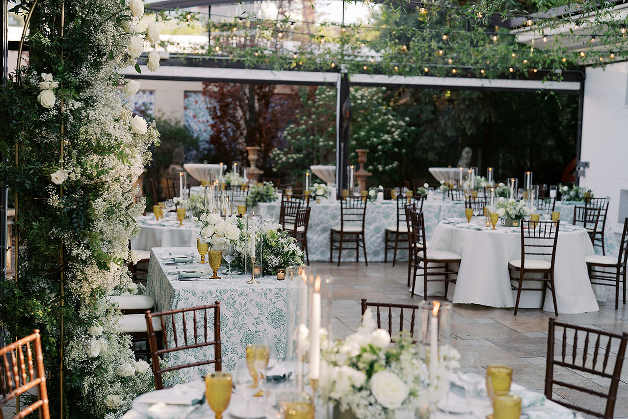 Detail of sweetheart table at Galleria Marchetti with green patterned linen, white florals and tall candles.