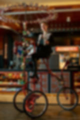 Performer riding a custom Wine Bike with spinning stemware canopy serving wine at an event by Bright Light Events