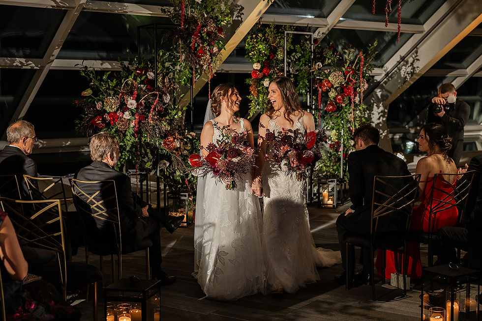 Brides getting married in a rooftop venue with lots of red flowers