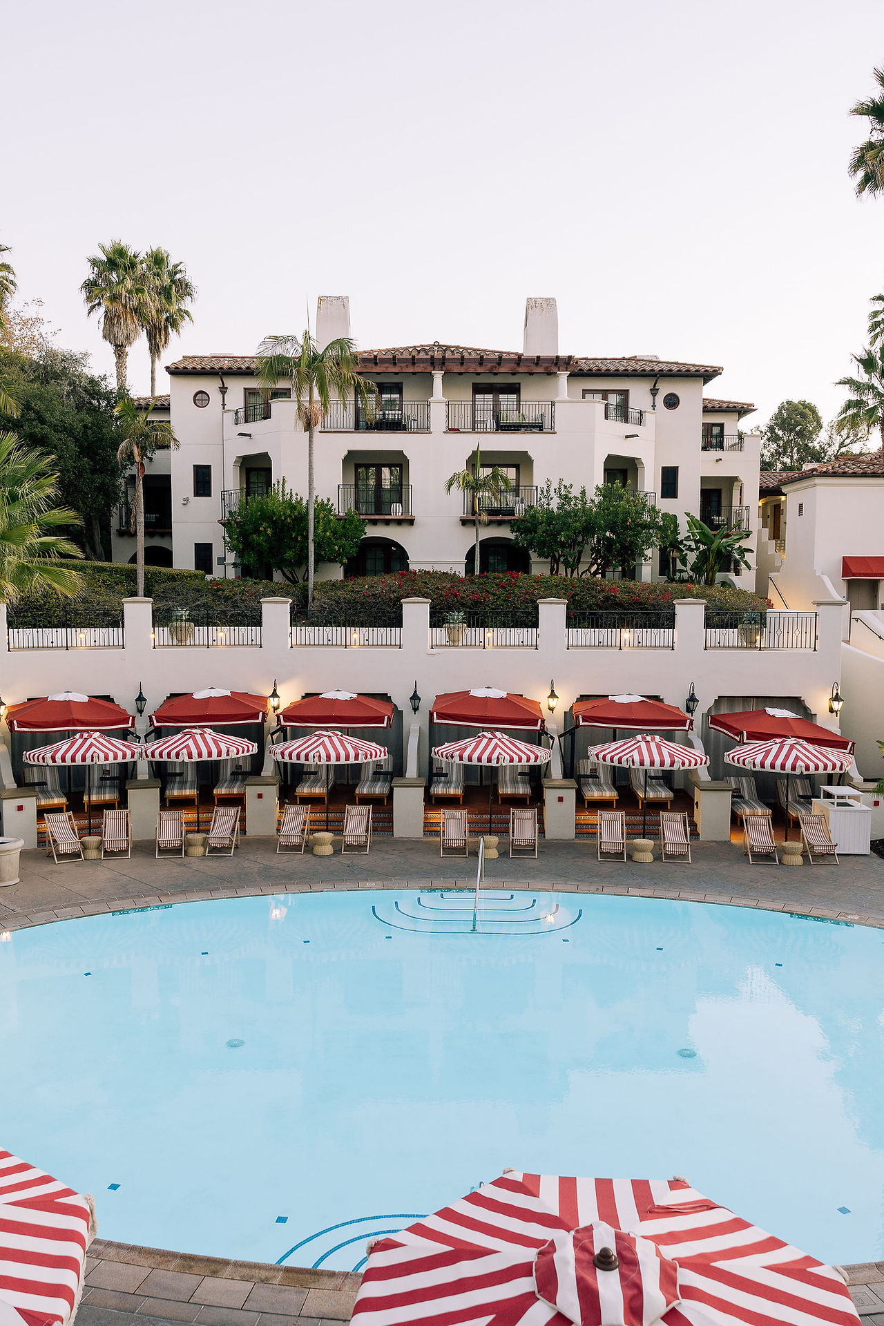 Resort pool with cabanas and red striped umbrellas at The Ritz-Carlton Bacara, perfect downtime during a wedding weekend.