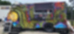 A food truck with a vibrant dragon mural and a neon "OPEN" sign is parked on gravel, with a menu displayed at the service window.
