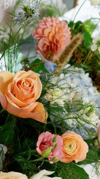 Bouquet of pink, orange, cream and blue flowers in a cane basket
