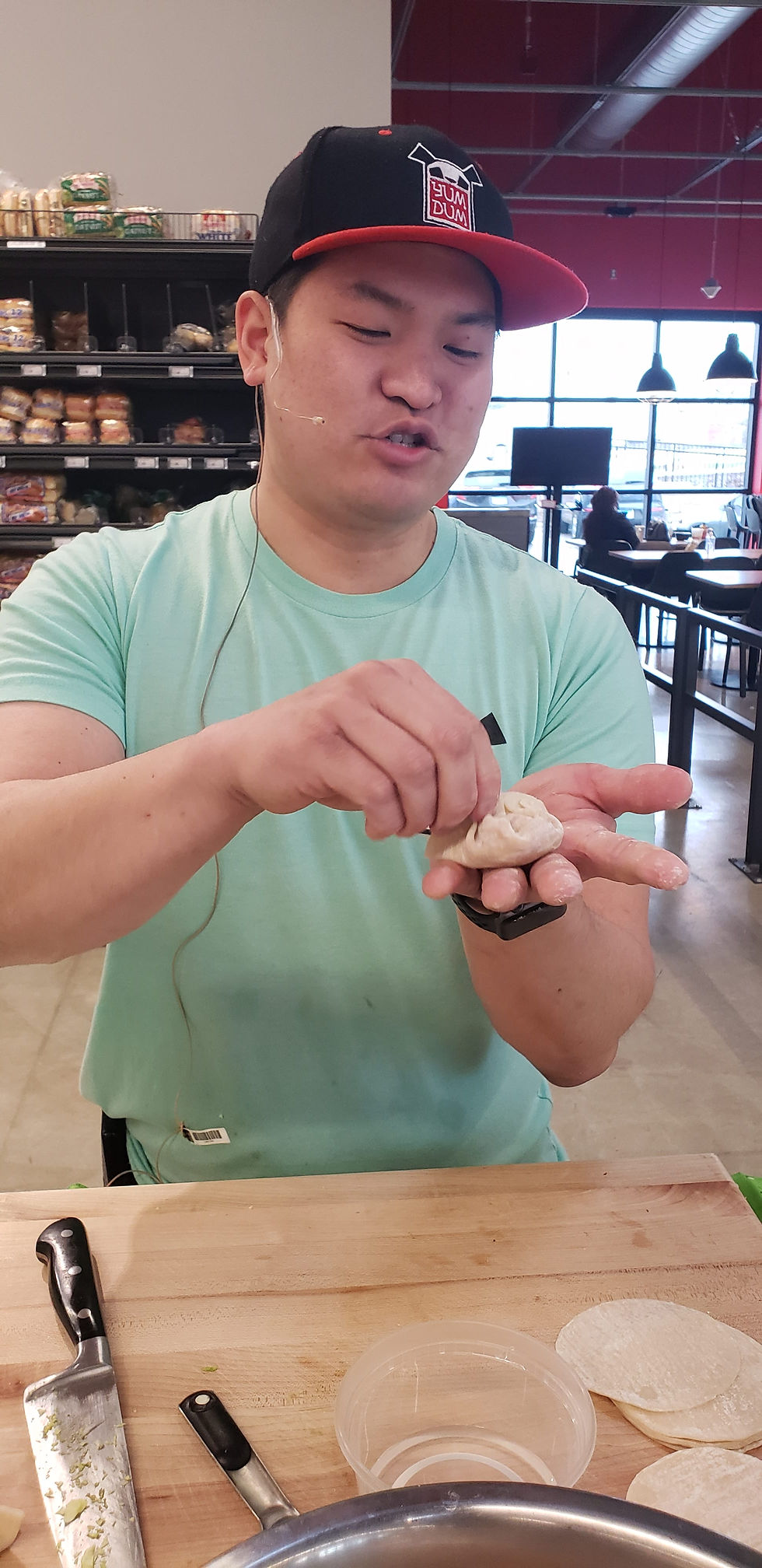 Chef from Yum Dum food truck hand-folding and crimping a pork dumpling during a live demonstration