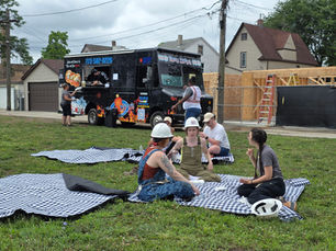Employees eating food truck catering on picnic blankets at an outdoor company lunch event