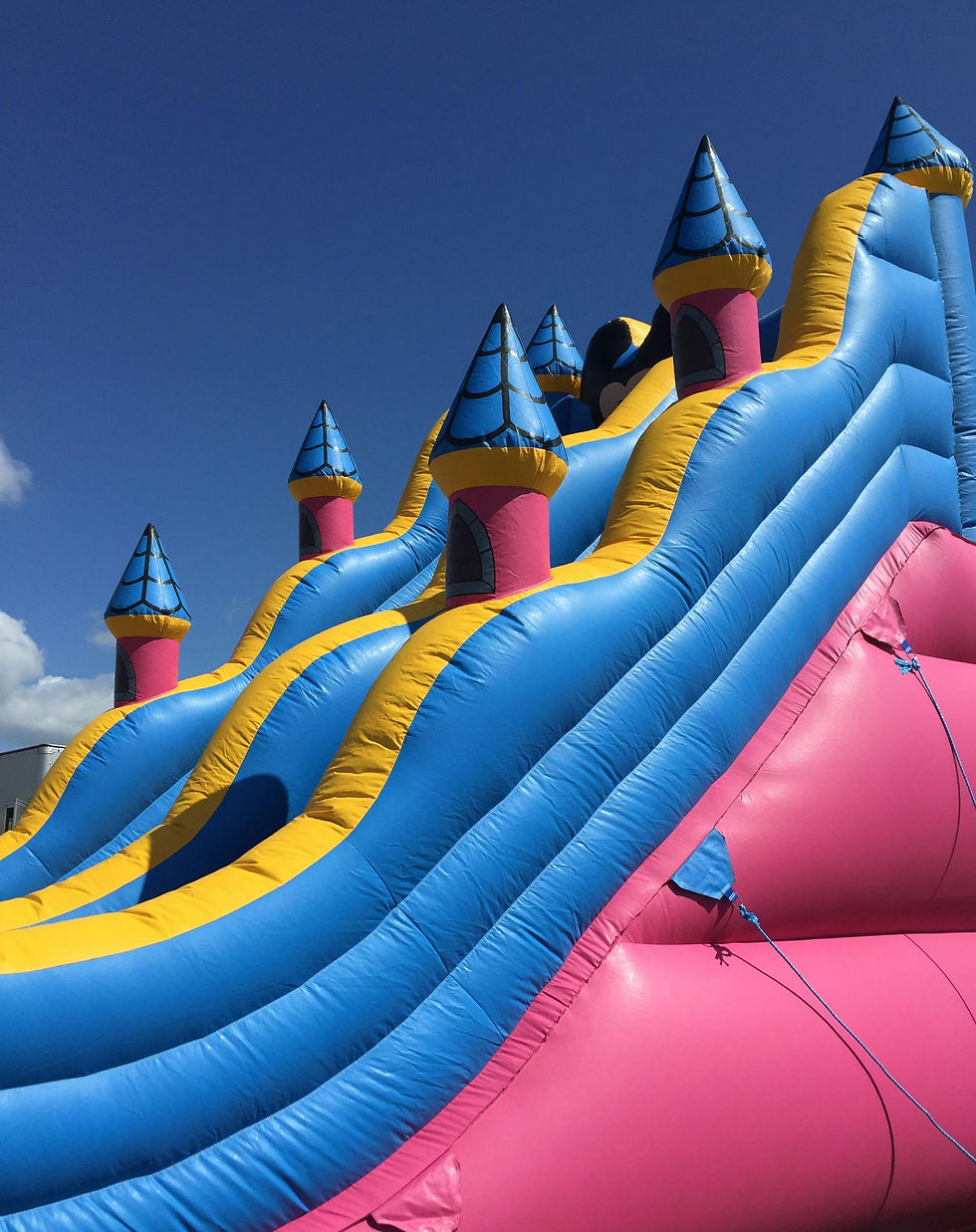 Large pink, blue and yellow bounce house with towers