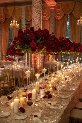 Towering red rose centerpiece over candlelit wedding head table with gold sequin linens and floating candles, Chicago luxury wedding by Frank Event Design