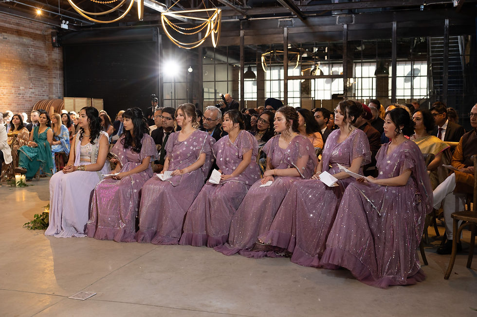 Friends and family members in traditional Indian clothing seated in the front row watching the wedding ceremony