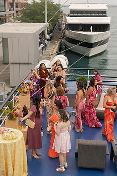 Aerial view of guests boarding the Spirit of Chicago at Navy Pier, with the Spirit of Navy Pier vessel docked alongside and Lake Michigan visible beyond, showing the vessel's open-air deck, floral installations, and lounge seating.